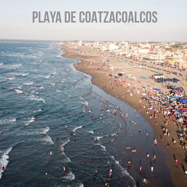 Vista aérea de la concurrida playa de Coatzacoalcos en Veracruz, mostrando a numerosos bañistas en el mar, sombrillas en la arena y el extenso malecón costero junto a la ciudad al fondo