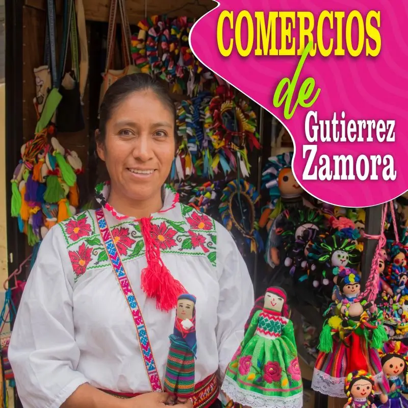 Mujer con blusa bordada tradicional sonriendo mientras sostiene muñecas de trapo artesanales. Texto integrado: Comercios de Gutiérrez Zamora.