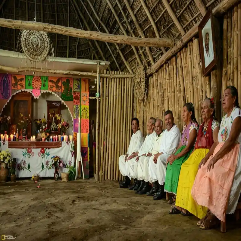 Abuelos y sabios totonacas sentados dentro de una choza tradicional frente a un altar en Papantla, Veracruz.