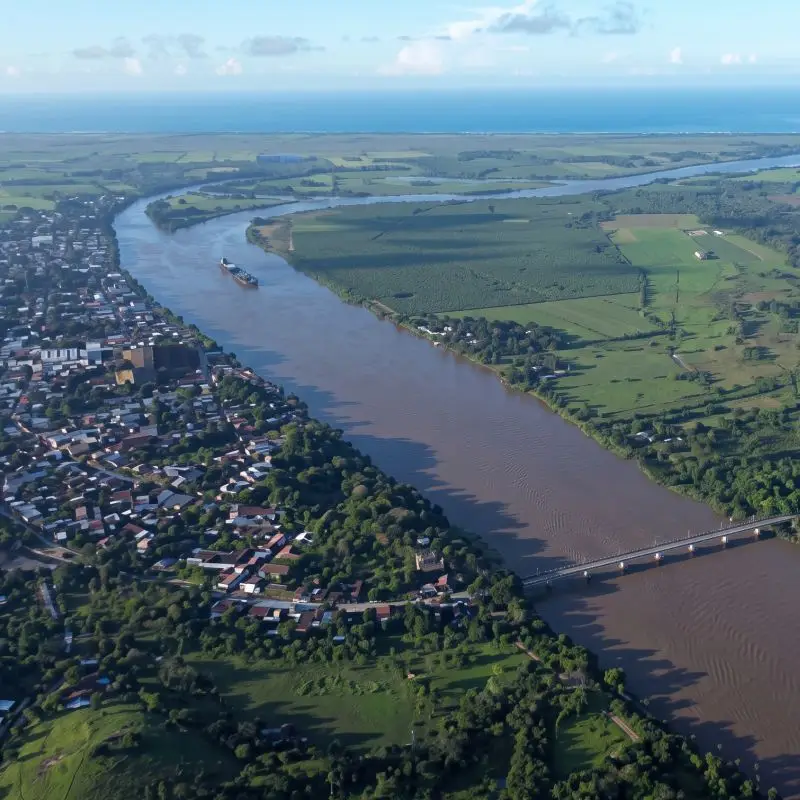 Panorámica aérea de dron del río Tecolutla, el puente vehicular y el pueblo de Gutiérrez Zamora, Veracruz, con el mar en el horizonte.