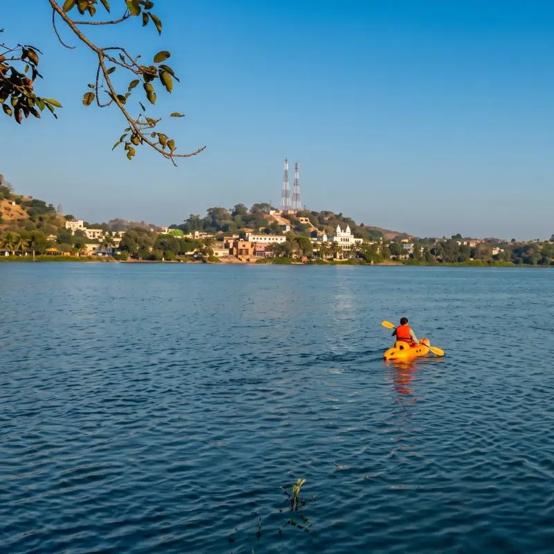 Persona practicando kayak en el río Tecolutla con el paisaje urbano y natural al fondo.