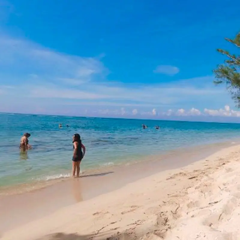 Una mujer de pie en la orilla de agua turquesa en Playa Majahual, una de las playas vírgenes cerca de Tamiahua, Veracruz, bajo un cielo azul claro, perfecta para paseos tranquilos.