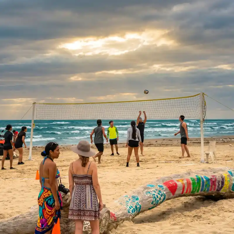 Grupo de jóvenes jugando voleibol en una playa de Tamiahua Veracruz con el mar de fondo y un cielo nublado dramático