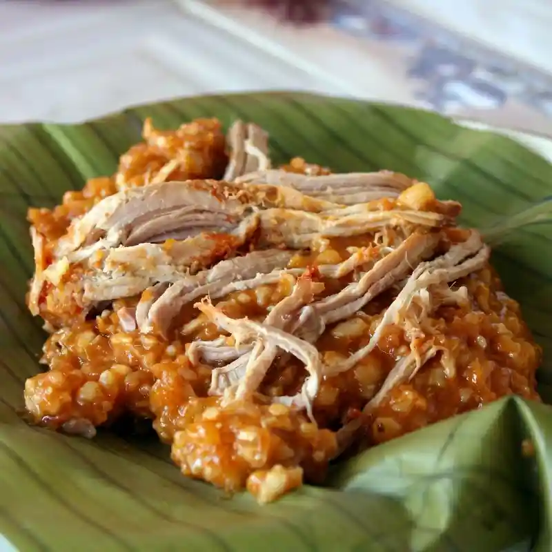 Primer plano de una porción de zacahuil tradicional huasteco servido sobre una hoja de plátano verde, mostrando la masa de maíz martajada y carne deshebrada, un platillo esencial de la comida típica de Tuxpan Veracruz.