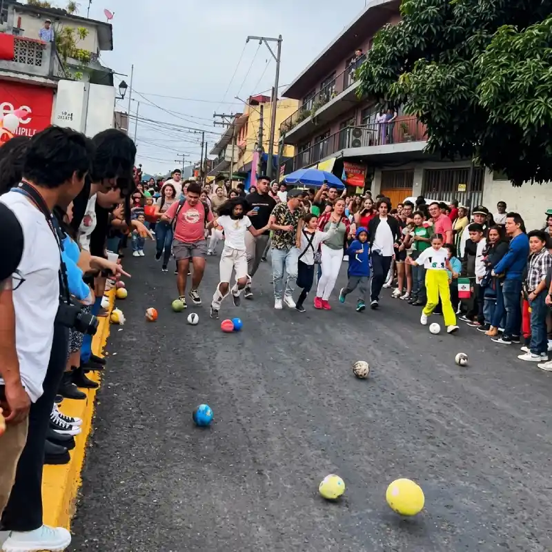 Participantes y espectadores corriendo junto a los melones rodantes durante la tradicional Carrera de Melones en una calle inclinada de Xalapa, Veracruz.