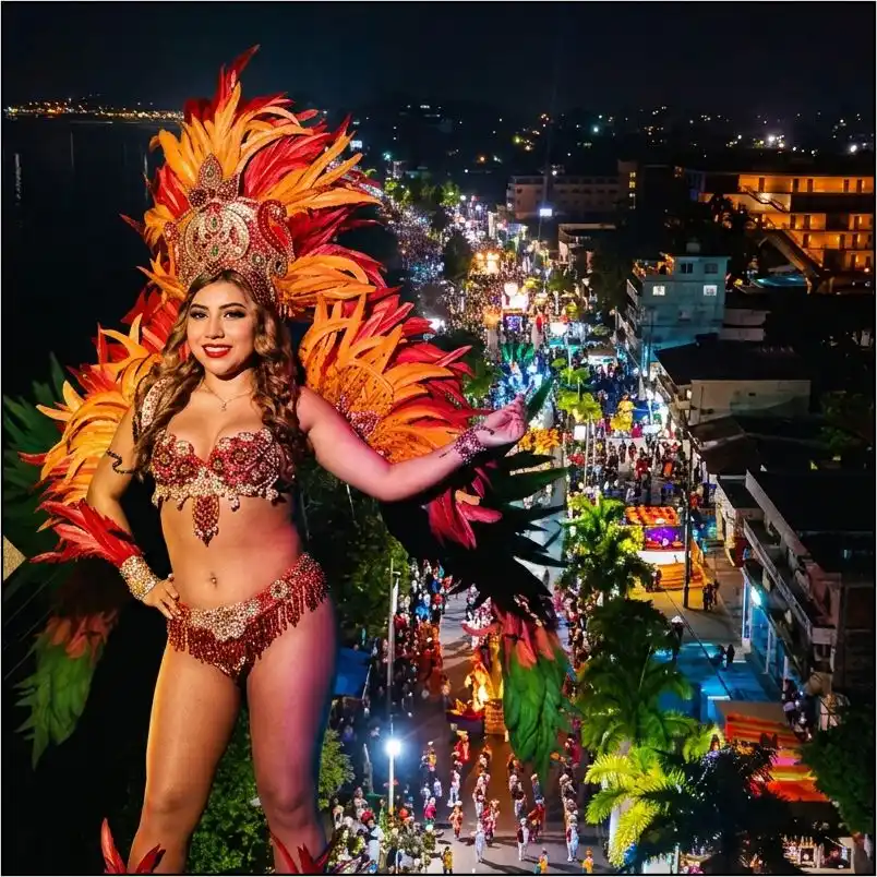 Bailarina con traje típico y vistoso tocado de plumas durante el desfile nocturno del Carnaval de Tuxpan Veracruz, con la avenida iluminada y gente celebrando al fondo.