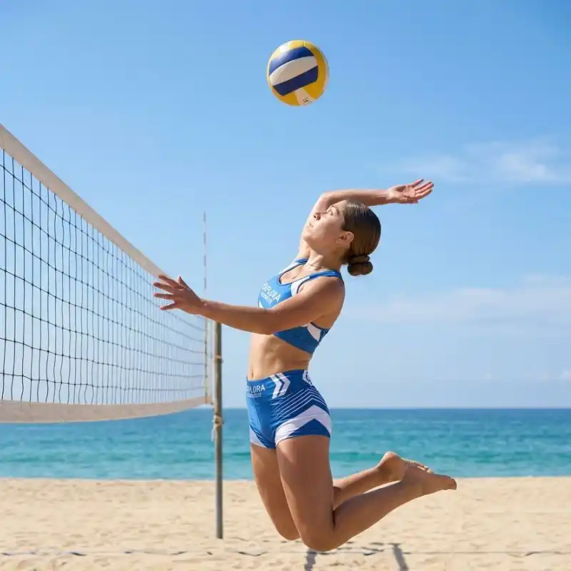 Atleta saltando para golpear el balón durante un torneo de voleibol de playa en la costa de Tuxpan Veracruz, con el mar y un cielo despejado de fondo.