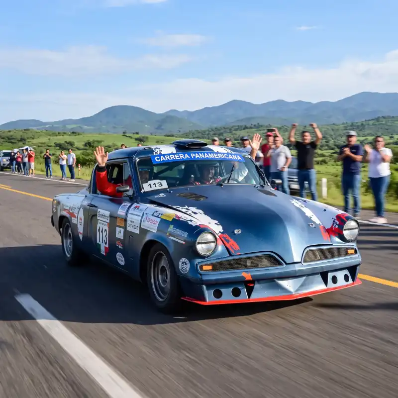 Pilotos saludando a los espectadores desde un auto clásico azul: resumen carrera panamericana veracruz