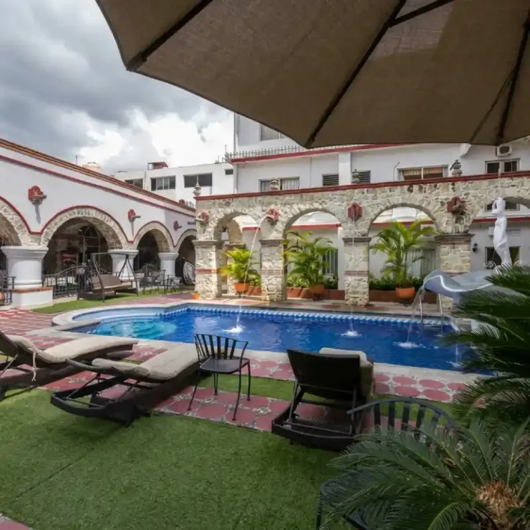 Área de descanso junto a la alberca en Hotel Tajín Papantla con camastros, sombrillas y pasto natural