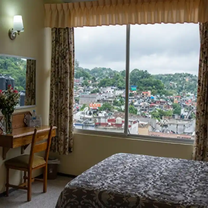 Habitación Accesible y Conectada en Hotel Tajín Papantla con escritorio de trabajo, cama confortable y amplio ventanal con vista panorámica a la ciudad.