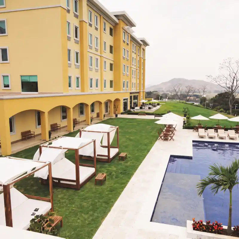 Áreas verdes y terraza junto a la alberca en el Hotel La Quinta by Wyndham Poza Rica, acondicionadas para eventos corporativos al aire libre y sesiones de networking.