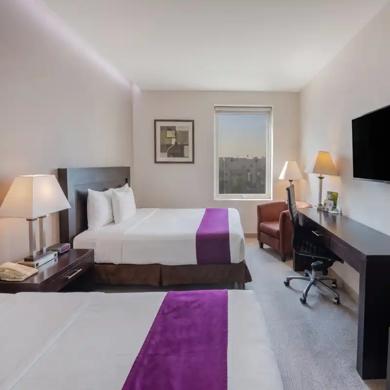 Habitación Estándar Doble Queen en el Hotel La Quinta by Wyndham Poza Rica, mostrando camas confortables y un amplio escritorio de trabajo, ideal para hospedaje corporativo en Veracruz.