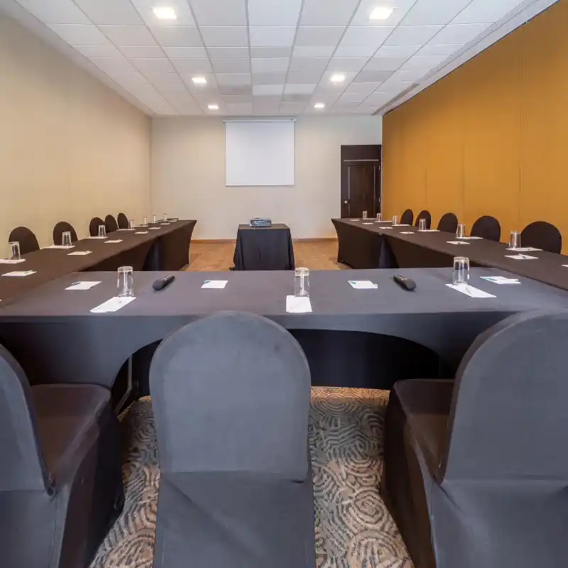 Sala modular de reuniones en el Hotel La Quinta by Wyndham Poza Rica, configurada en formato de herradura con pantalla de proyección, ideal para eventos corporativos y juntas de negocios.