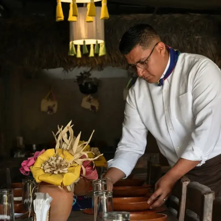 Mesero preparando mesa con vajilla de barro y artesanías en el Restaurante Totonaco del Hotel Tajín Papantla.
