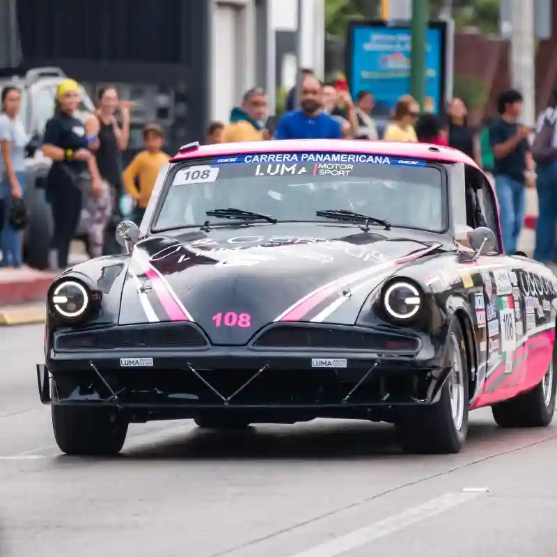 Auto clásico negro recorriendo las calles entre espectadores en la Carrera Panamericana Veracruz