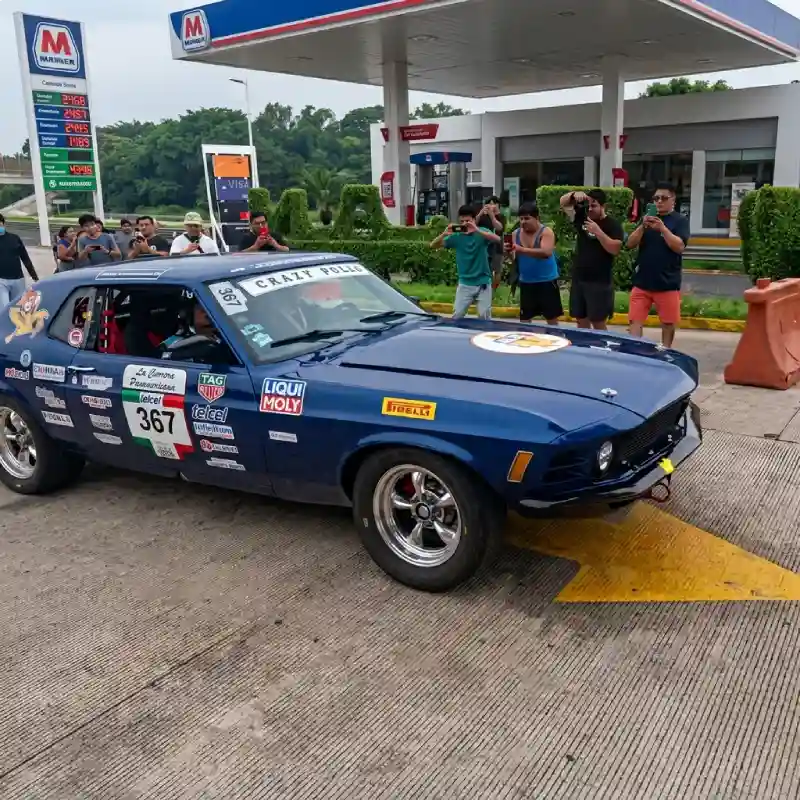 Auto clásico de competencia frente a una gasolinera local durante la ruta de la Carrera Panamericana en Veracruz