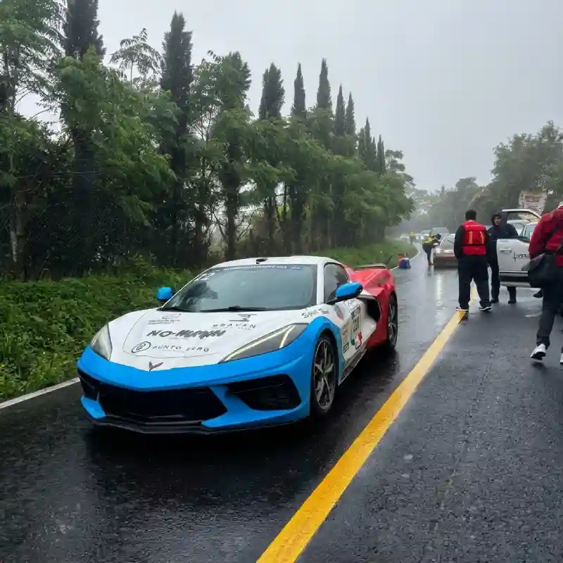 Auto deportivo azul en carretera mojada durante la ruta de la Carrera Panamericana en Veracruz