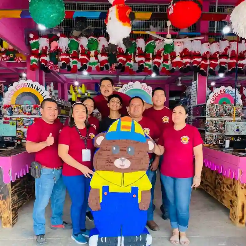 Equipo de servicio al cliente de Grupo Dulcelandia en Papantla posando con piñata del Oso Golosin en tienda decorada.