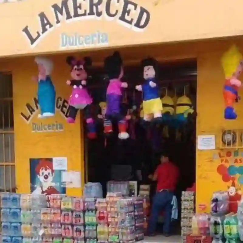 Fachada de Dulcería La Merced de Grupo Dulcelandia en Papantla con piñatas y paquetes de agua o refrescos en exhibición.
