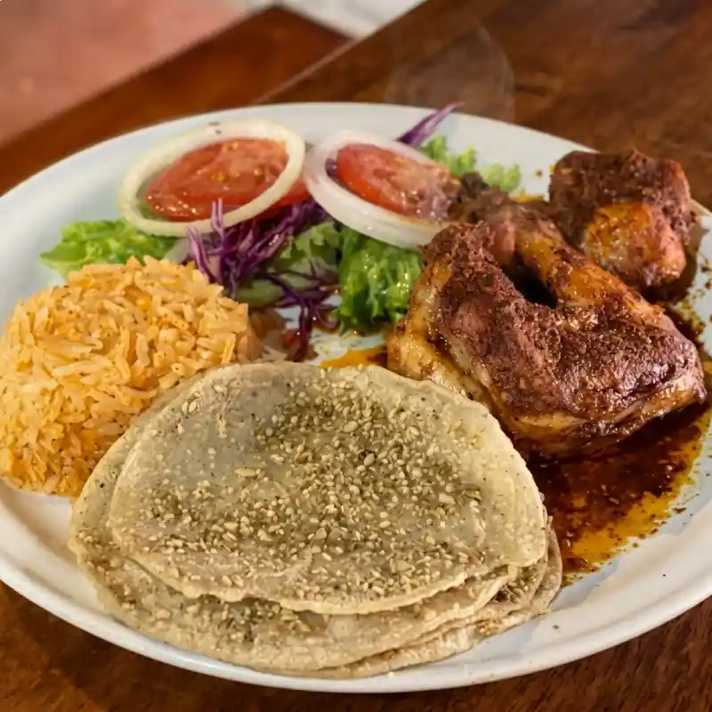 Plato tradicional de empipianadas totonacas con salsa de pepita de calabaza tostada, pollo adobado, arroz y ensalada en Restaurante Nakú, platillo insignia del Alma Totonaca en Explora Veracruz.