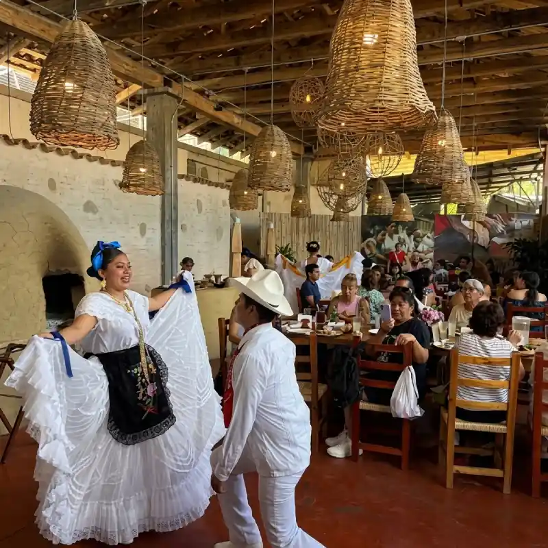 Pareja ejecutando el baile folclórico del son jarocho entre comensales en el salón principal de Restaurante Nakú, símbolo de la cultura viva del Alma Totonaca en Explora Veracruz.