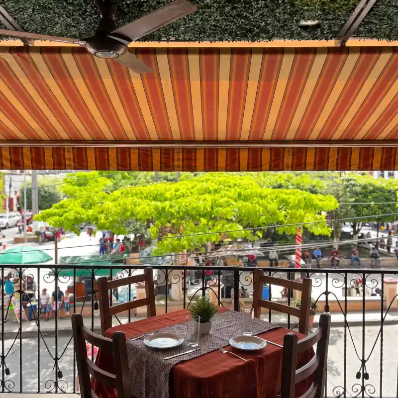 Mesa reservada en la terraza pet-friendly del Restaurante Plaza Pardo en Papantla con toldo desplegado, ventilador de techo y vista directa al parque central.